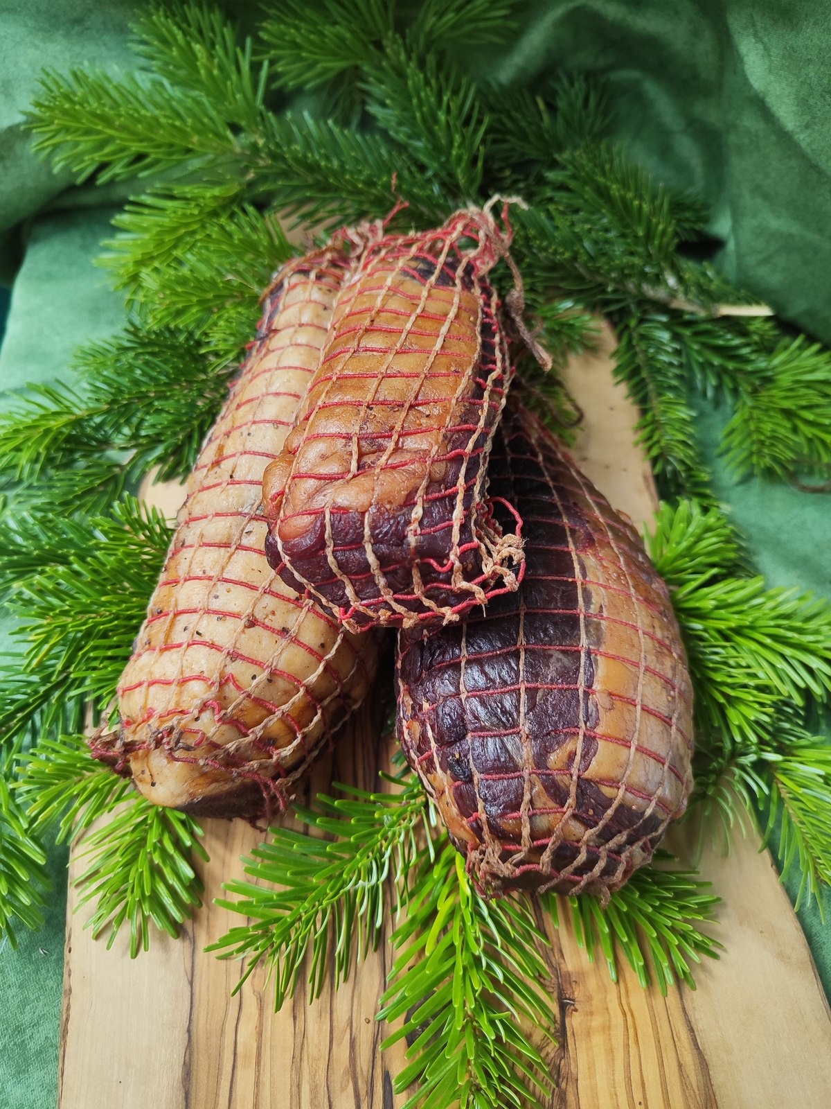 Wildschweinschinken im Reifenetz vor Tannengrün